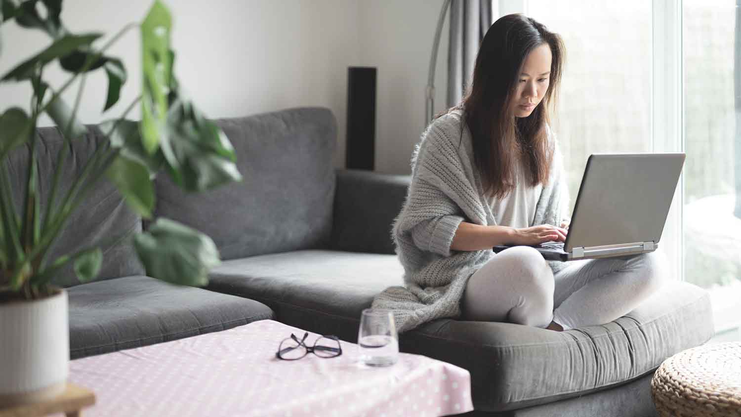 Woman sitting on a couch working on a laptop computer
