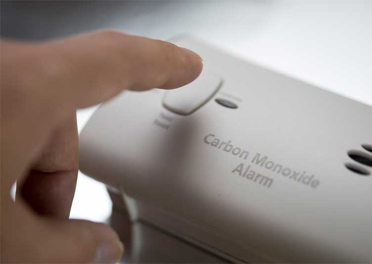 Closeup of a finger testing a carbon monoxide detector