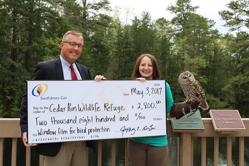 SJG President and Cedar Wildlife Refuge senior educator pose with check